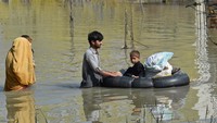 Seorang anak kecil yang terkena dampak banjir, dipindahkan ke tempat yang lebih aman menggunakan perahu karet. (Abdul Majeet/Getty Images)