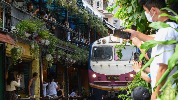 Tourists take photos of a train passing through an old residential area in central Hanoi on August 28, 2022. (Photo by Nhac NGUYEN / AFP) (Photo by NHAC NGUYEN/AFP via Getty Images)