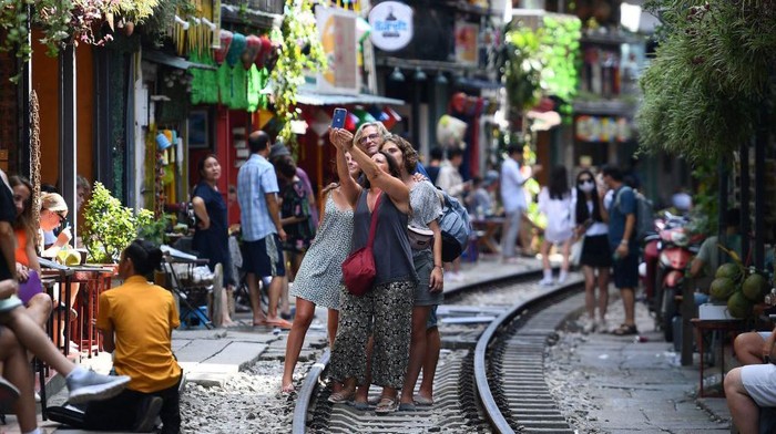 Tourists take photos of a train passing through an old residential area in central Hanoi on August 28, 2022. (Photo by Nhac NGUYEN / AFP) (Photo by NHAC NGUYEN/AFP via Getty Images)