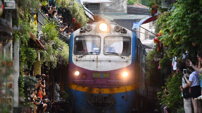Tourists take photos of a train passing through an old residential area in central Hanoi on August 28, 2022. (Photo by Nhac NGUYEN / AFP) (Photo by NHAC NGUYEN/AFP via Getty Images)