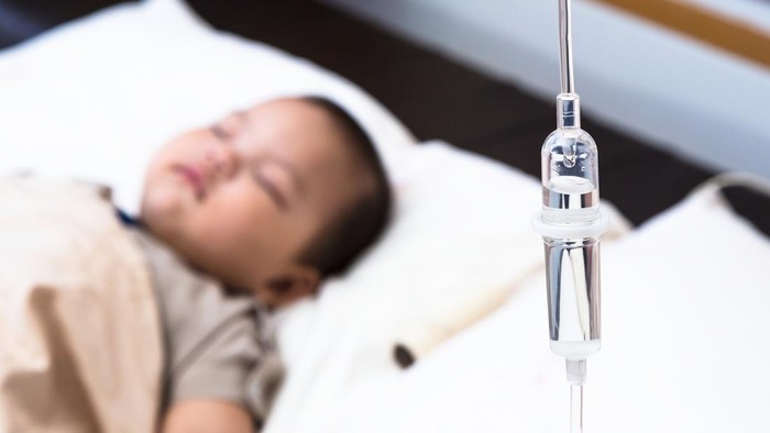 5 months old baby with dehydration, receiving medication through intravenous fluid therapy while asleep in hospital bed, focus on drip chamber