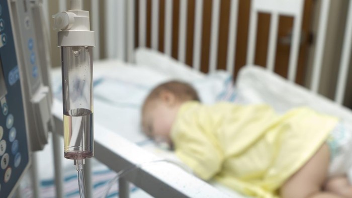 A 10 month old baby is sleeping in a crib in the hospital while receiving fluids from the fluid pump.See related: