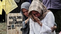 Salah satu ibu dari korban tewas menangis di makam anaknya.