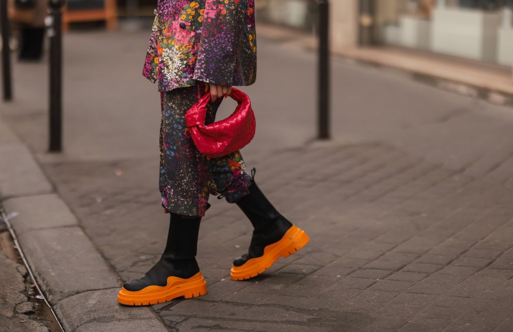 PARIS, FRANCE - MARCH 02: Sonia Lyson wearing Bottega Veneta black and orange leather boots, Bottega Veneta berry mini Jodie, Rotate matching colorful flower suit on March 02, 2022 in Paris, France. (Photo by Jeremy Moeller/Getty Images)