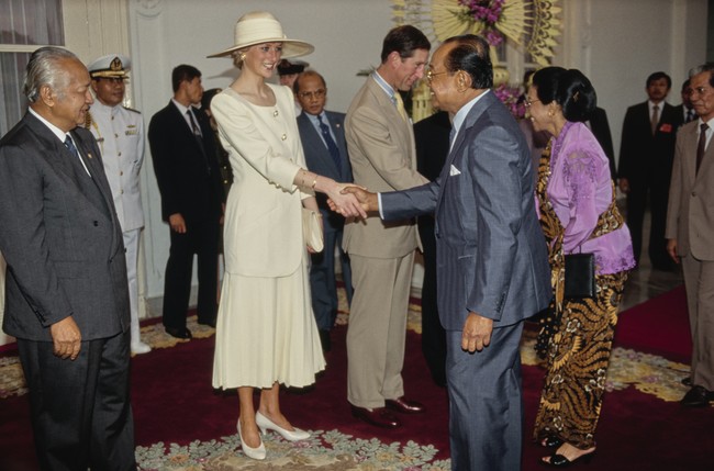 Pangeran Charles dan Putri Diana disambut Presiden Soeharto di Istana Merdeka. Pertama kali menapakkan kaki di Indonesia, Putri Diana berbalut blus krem dan rok lipit maksi senada rancangan desainer Inggris Catherine Walker. Hampir semua pakaian Putri Diana untuk tur Indonesia ini dirancang oleh Catherine yang karyanya sekarang kerap menemani gaya Kate Middleton, istri dari Pangeran William. (Foto: Tim Graham Photo Library via Getty Images)