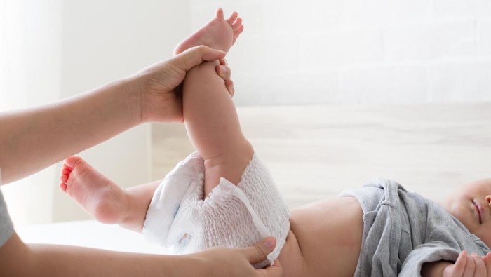 llustrasi Tips Memilih Popok Bayi Newborn Mother changing diaper for her son on white bed in bedroom