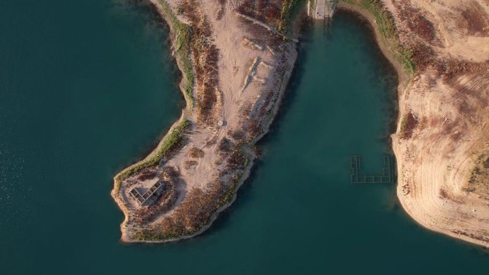 Potret Desa di Dasar Bendungan Irak yang Muncul Lagi Imbas Kekeringan An aerial view shows the remains of the submerged Gary Qasruka village, which was abandoned in 1985 and had partly resurfaced recently following a large drop in water level of the Dohuk Dam due to drought, in the northern Iraqi city of Dohuk in the autonomous Kurdish region on August 28, 2022. (Photo by Ismael ADNAN / AFP) (Photo by ISMAEL ADNAN/AFP via Getty Images)