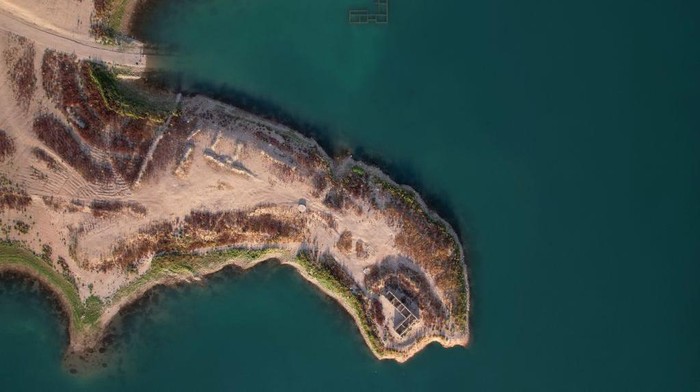 Potret Desa di Dasar Bendungan Irak yang Muncul Lagi Imbas Kekeringan An aerial view shows the remains of the submerged Gary Qasruka village, which was abandoned in 1985 and had partly resurfaced recently following a large drop in water level of the Dohuk Dam due to drought, in the northern Iraqi city of Dohuk in the autonomous Kurdish region on August 28, 2022. (Photo by Ismael ADNAN / AFP) (Photo by ISMAEL ADNAN/AFP via Getty Images)