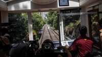 Kereta Peak Tram generasi keenam punya kapasitas 210 penumpang dengan jendela lebih luas. Sejumlah media yang diundang untuk tur Peak Tram generasi keenam memanfaatkan momen ini untuk berfoto. (Isaac Lawrence/AFP/Getty Images)