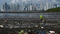 Seorang pria mengumpulkan sampah yang menyelimuti pantai Costa del Este, di Panama City, Panama, Senin (19/4/2021). (Luis Acosta/AFP/Getty Images)  