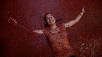 Seorang peserta perang tomat nampak bersuka ria berbaring di bubur tomat selama festival La Tomatina tahunan di Bunol, Spanyol.