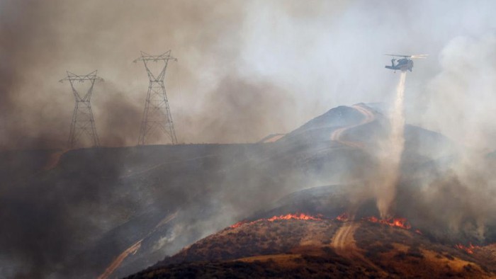 CASTAIC, CALIFORNIA - AUGUST 31: Firefighters work as a tow truck tows away the trailer of a truck while the Route Fire burns on August 31, 2022 near Castaic, California. Evacuations have been ordered as the brush fire has scorched more than 600 acres and closed down the 5 freeway amid a heat wave in Southern California. (Photo by Mario Tama/Getty Images)
