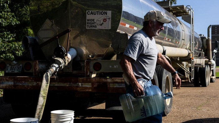 Krisis Air Bersih di Jackson JACKSON, MS - AUGUST 31: Jamiya Williams loads her car with two cases of bottled water at a Salvation Army of Jackson and Walmart distribution site at a Walmart on August 31, 2022 in Jackson, Mississippi. Jackson is experiencing a third day without reliable water service after river flooding caused the main treatment facility to fail. Late Tuesday night, President Joe Biden declared an emergency amid the crisis. (Photo by Brad Vest/Getty Images)