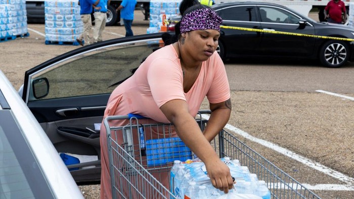 Krisis Air Bersih di Jackson JACKSON, MS - AUGUST 31: Jamiya Williams loads her car with two cases of bottled water at a Salvation Army of Jackson and Walmart distribution site at a Walmart on August 31, 2022 in Jackson, Mississippi. Jackson is experiencing a third day without reliable water service after river flooding caused the main treatment facility to fail. Late Tuesday night, President Joe Biden declared an emergency amid the crisis. (Photo by Brad Vest/Getty Images)