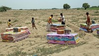 Bantuan kemanusiaan dibagikan di padang pasir yang panas dan berdebu. Selain masalah keamanan akibat perang, harga pangan yang melonjak pun menjadi masalah lain untuk para pengungsi. (Khaled Ziad/AFP/Getty Images)  
