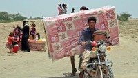 Paket bantuan dibawa menggunakan sepeda motor atau dipanggul. Banyak warga yang harus pergi dari rumahnya demi keamanan dan menetap di pusat-pusat pengungsian. (Khaled Ziad/AFP/Getty Images)  