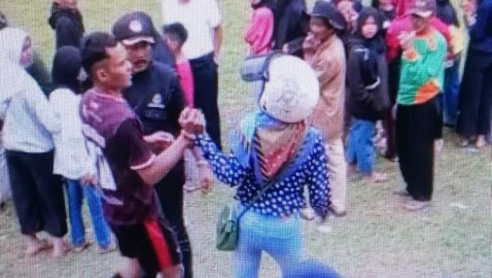 Seorang perempuan menarik pesepakbola keluar dari lapangan.