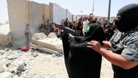 Seorang anggota sayap militer yang berafiliasi dengan ulama Syiah Moqtada al-Sadr, membantu seorang wanita menembakkan senapan mesin selama bentrokan dengan pasukan keamanan Irak di Zona Hijau Baghdad. Pemerintah Irak telah memberlakukan jam malam untuk mengendalikan kerusuhan itu.