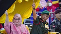 Raja Malaysia Sultan Abdullah Sultan Ahmad Shah dan Ratu Tunku Azizah Aminah Maimunah Iskandariah melambaikan tangan saat mereka tiba untuk perayaan Hari Kemerdekaan Malaysia ke-65 di Lapangan Kemerdekaan di Kuala Lumpur, Malaysia.