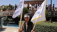 Pemuda Taliban membawa bendera dalam parade tersebut. 