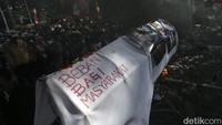 Usai berorasi massa mulai memaksa masuk melewati pagar berduri, mereka juga membakar keranda mayat yang dibawanya.