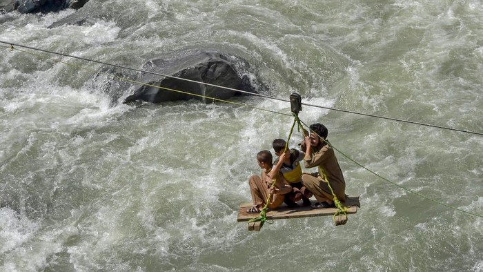 Warga Pakistan Nekat Sebrangi Sungai Pakai Gondola Akibat Jembatan Disapu Banjir TOPSHOT - Local residents use a temporary cradle service to cross the river Swat after heavy rains in Bahrain town of Swat valley in Khyber Pakhtunkhwa province on August 31, 2022. - Army helicopters flew sorties over cut-off areas in Pakistan's mountainous north on August 31 and rescue parties fanned out across waterlogged plains in the south as misery mounted for millions trapped by the worst floods in the country's history. (Photo by Abdul MAJEED / AFP) (Photo by ABDUL MAJEED/AFP via Getty Images)