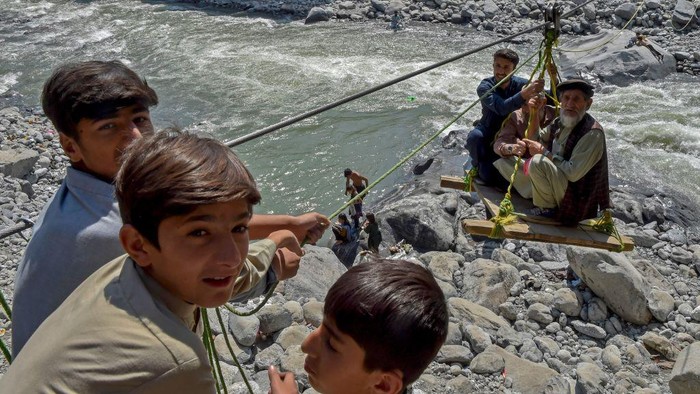 Warga Pakistan Nekat Sebrangi Sungai Pakai Gondola Akibat Jembatan Disapu Banjir TOPSHOT - Local residents use a temporary cradle service to cross the river Swat after heavy rains in Bahrain town of Swat valley in Khyber Pakhtunkhwa province on August 31, 2022. - Army helicopters flew sorties over cut-off areas in Pakistan's mountainous north on August 31 and rescue parties fanned out across waterlogged plains in the south as misery mounted for millions trapped by the worst floods in the country's history. (Photo by Abdul MAJEED / AFP) (Photo by ABDUL MAJEED/AFP via Getty Images)