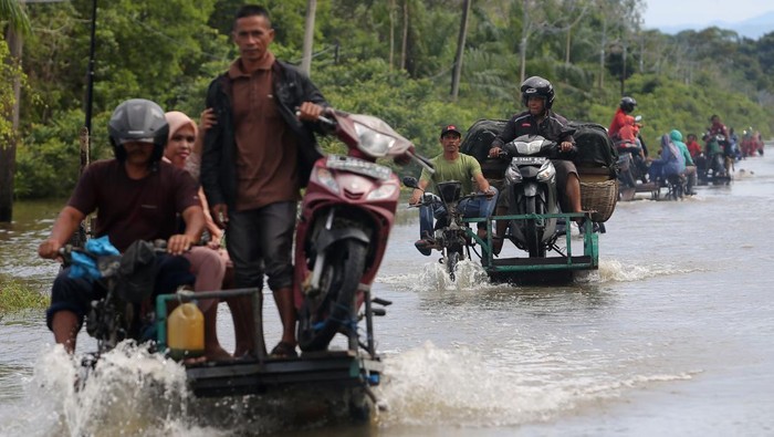 Ada Jasa Angkut Motor Lintasi Banjir di Aceh Pengendara memanfaatkan jasa angkut kendaraan roda dua untuk melintasi jalan yang terendam banjir di Desa Layung, Bubon, Aceh Barat, Aceh, Jumat (2/9/2022). Tingginya intensitas hujan menyebabkan empat sungai dikawasan itu meluap dan merendam puluhan rumah warga serta ratusan hektare lahan pertanian/perkebunan dengan ketinggian air 30 cm sampai 100 cm di Kecamatan Arongan Lam Balek, Woyla Barat, Bubon, Kaway XVI, Meureubo, Samatiga dan Kecamatan Johan Pahlawan. ANTARA FOTO/Syifa Yulinnas/nym.
