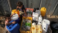 Dua orang anak laki-laki yang menunggu antrean dan terlihat mereka tak hanya membawa satu atau dua botol, tetapi mereka membawa beberapa botol serta jeriken.