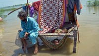 Seorang pria yang terkena dampak banjir duduk bersama anak-anaknya di distrik Jaffarabad, provinsi Balochistan, Pakistan, Rabu (31/8/2022). (Fida Hussain/AFP/Getty Images)  