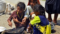 Gadis-gadis pengungsi memasak ikan setelah berlindung dari rumah mereka yang terkena banjir di pinggir jalan di Multan, Pakistan, Rabu (31/8/2022). Anak-anak Pakistan harus menderita akibat banjir bandang tersebut. (AP Photo/Shazia Bhatti)  