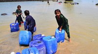 Anak-anak korban banjir Pakistan membawa jeriken berisi air minum bersih, Rabu (31/8/2022). Banjir dahsyat ini juga menimbulkan langkanya air bersih. Anak-anak harus ikut mengambil air bersih dan menerjang banjir yang masih menggenangi wilayah mereka. (Shakeel Ahmed/Getty Images)  