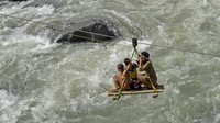 Anak-anak menyebrangi sungai dengan gondola di kota lembah Swat Bahrain di provinsi Khyber Pakhtunkhwa, Pakistan, Rabu (31/8/2022). Jembatan yang hancur membuat warga harus menyebrang dengan gondola yang berbahaya. (Abdul Majeed/AFP/Getty Images)   