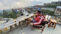 Terakhir ini momen santai Andi, yang ngopi dengan pemandangan bukti dan perumahan yang asri dan sejuk. Foto: Site News