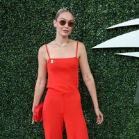 Gigi Hadid tampil menarik perhatian dengan jumpsuit backless merah dan sneakers yang matching dengan tas Louis Vuitton yang dibawanya. Foto: Dok. Photo by Gotham/GC Images, Jean Catuffe/GC Image