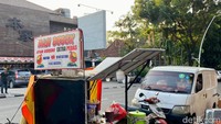 Tempat jualannya sederhana, hanya memakai gerobak motor yang diparkir di pinggir jalan. Pun untuk area bersantapnya hanya kursi dan meja plastik.