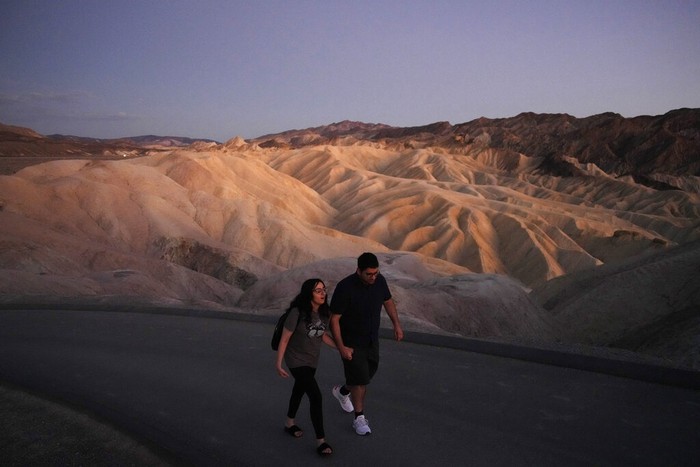People visit a thermometer at the Furnace Creek Visitor Center, Thursday, Sept. 1, 2022, in Death Valley National Park, Calif. The thermometer is not official but is a popular photo spot. (AP Photo/John Locher)