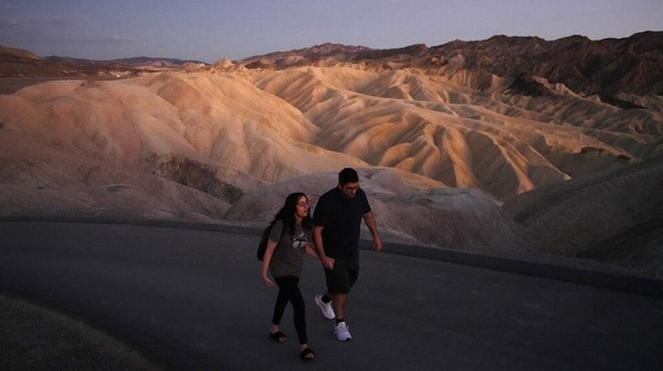 Sepasang turis melintasi Death Valley yang terkenal dengan pemandangannya. Akhir tahun lalu, lembah ini jadi tempat terpanas di dunia.  