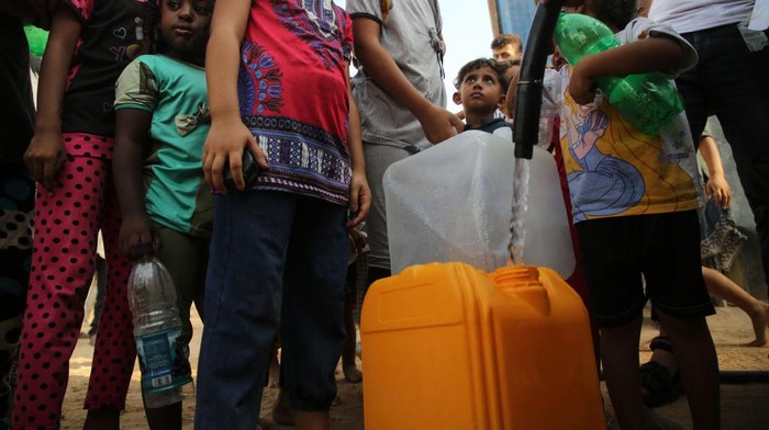 Palestinian children fill bottles with drinking water, in a poor neighborhood in Beit Lahia in the northern Gaza Strip, on 01 September 2022. (Photo by Majdi Fathi/NurPhoto via Getty Images)