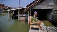 Nenek Mariah duduk di kursi depan rumahnya setiap hari sambil menunggu rumahnya cukup kering dari banjir agar bisa masuk lagi, Minggu (31/7/2022).