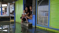 Jaka Sadewa duduk di depan rumahnya bersama istrinya Sri Wahyuni dan putranya Bima. Terlihat depan rumahnya seperti kolam renang. Jaka mengatakan jika keluarganya mempunyai sumber daya apapun, mereka akan segera meninggalkan tempatnya dan pindah ke tempat yang lebih baik, Minggu (31/7/2022).