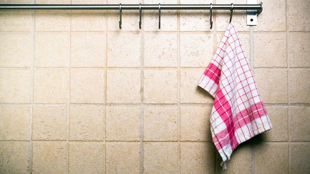 Kitchen utensils, cloth hanging alone on wall.