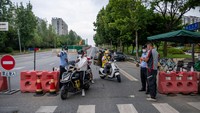 Petugas polisi memeriksa warga saat berjaga di salah satu titik jalan di tengah pembatasan akibat merebaknya virus corona di Chengdu. (Liu Zhongjun/CNS/Getty Images)