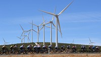 Para pebalap melintasi deretan turbin angin dalam etape 13 La Vuelta Espana 2022, Jumat (3/9/2022). Meski Evenepoel mendominasi di puncak klasemen sementara,  ia belum bisa bernafas lega. Ada Roglic dan Enric Mas yang mengintai. Selisihnya cukup tipis, 1 menit 34 detik dan 2 menit 1 detik. (Justin Setterfield/Getty Images)