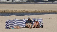 Sebagian warga berjemur di bawah sinar matahari di pinggir pantai laut Baltik, Debki, Polandia.
