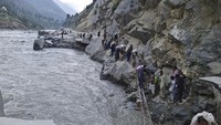 Penduduk setempat melintasi sebagian jalan yang rusak akibat banjir di Lembah Kalam di Pakistan utara, Minggu (4/9/2022).
