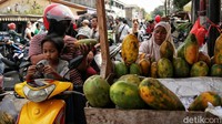 Pembeli menawar produk pepaya dari atas kendaraan roda duanya. Harga-harga dilaporkan mulai naik dipicu kenaikan harga BBM.  