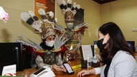 Customer service Bank Mega KCP Jakarta Cinere memberikan pelayanan dengan memakai pakaian adat Suku Dayak.