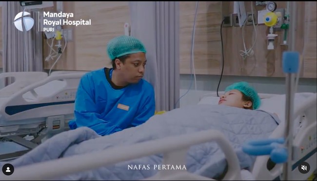 Dalam foto terlihat Indah dan suaminya yang sudah berganti pakaian dan siap menuju ke ruang operasi. Arie Kriting tampak setia menemani untuk memberikan dukungan kepada sang istri. Foto: Instagram/@indahpermatas