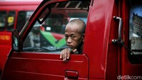 Salah satu penumpang termenung saat menunggu angkot. Menurut salah satu sopir, beberapa angkot di kawasan itu telah menaikan tarif ongkosnya.  
